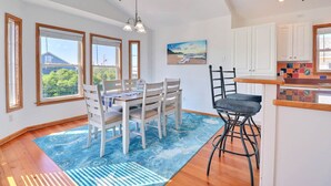 Un comedor con una mesa y sillas, un taburete de bar, y una zona de cocina con armarios y encimera.