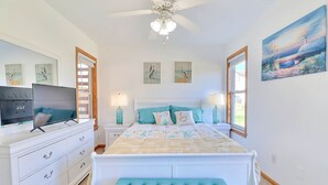 Un dormitorio con cama, televisor, cómoda y obras de arte en las paredes.