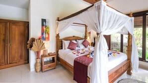 A four-poster bed with a canopy, wooden headboard, and a bedside table with a vase and a picture frame. - Villa Tirtha Amertha Ubud (Ubud)