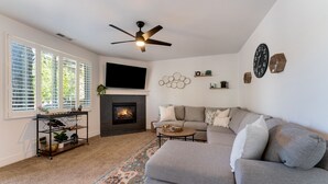 A living room with a fireplace, a sofa, a coffee table, and a TV. - Newly Renovated Mountain Getaway Stocked for Fun! - (Flagstaff)