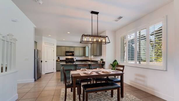 A spacious kitchen with a dining area, featuring a large island, modern appliances, and a pendant light. - Newly Renovated Mountain Getaway Stocked for Fun! - (Flagstaff)