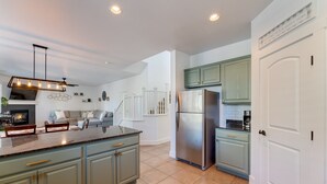 A modern kitchen with light blue cabinets, a stainless steel refrigerator, and a built-in island with seating. - Newly Renovated Mountain Getaway Stocked for Fun! - (Flagstaff)