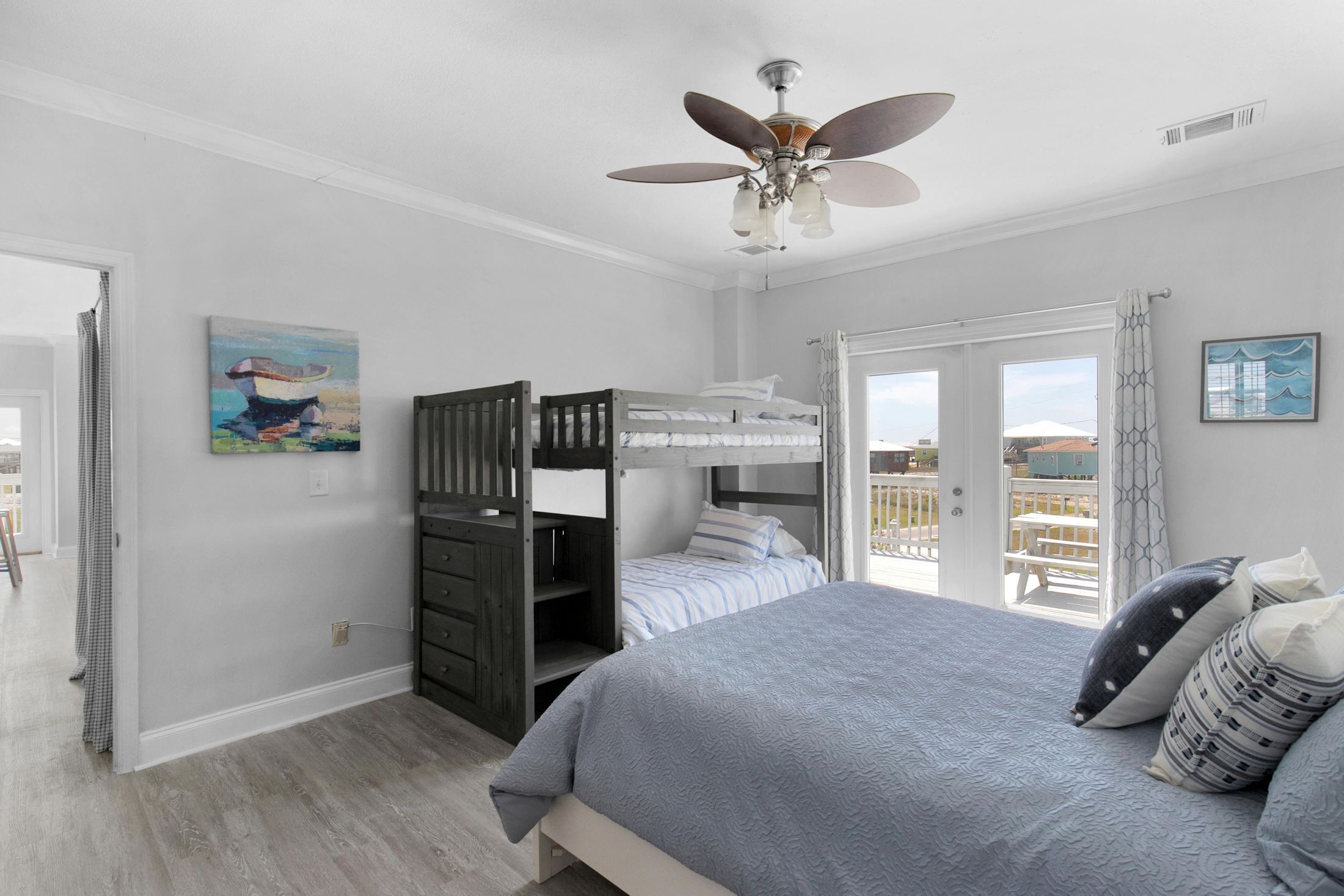 A bedroom with a bunk bed, a ceiling fan, and a balcony with a view.