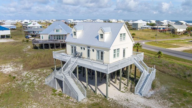 A coastal house with a balcony and a staircase leading to a pier.