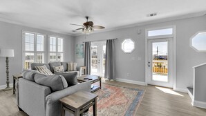 A living room with a gray sofa, a wooden coffee table, and a large window with blinds.