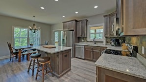A spacious kitchen with granite countertops, wooden cabinets, and stainless steel appliances. - Blue Heaven, Family vacation near Ocoee River, McCaysville, and Blue Ridge Area (Copperhill)