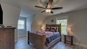 A bedroom with a sloped ceiling, a wooden bed, a ceiling fan, a nightstand, a lamp, and a window with blinds. - Blue Heaven, Family vacation near Ocoee River, McCaysville, and Blue Ridge Area (Copperhill)