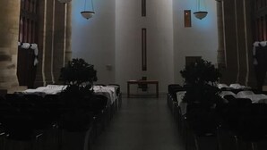 A church interior with rows of pews, a central aisle, and hanging chandeliers.