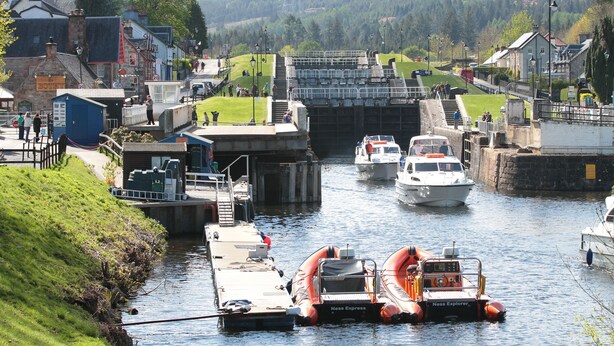A canal with boats, a lock system, and buildings along the banks.