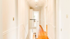 A hallway with white walls and wooden flooring, leading to a door at the end. - Historic Annapolis Union House with Private Patio & Free Off-Site Parking (Annapolis)