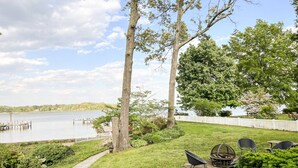 A backyard with a fire pit, outdoor seating, and a view of a lake.