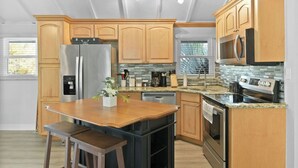 A modern kitchen with wooden cabinets, stainless steel appliances, a granite countertop, and a central island with seating.