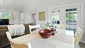A dining area with a wooden table, white chairs, and a large bowl centerpiece.