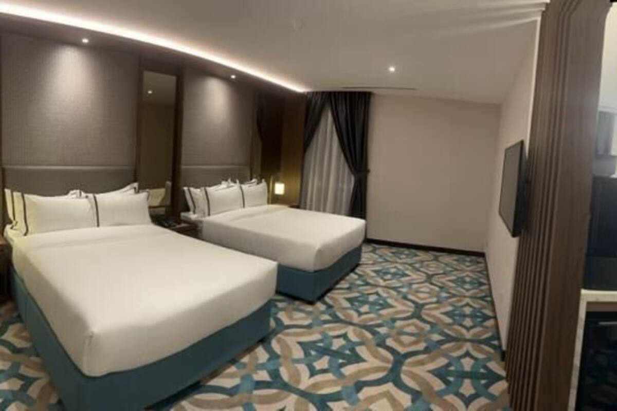 A hotel room with two beds, a desk with a chair, a TV, and a mirror.