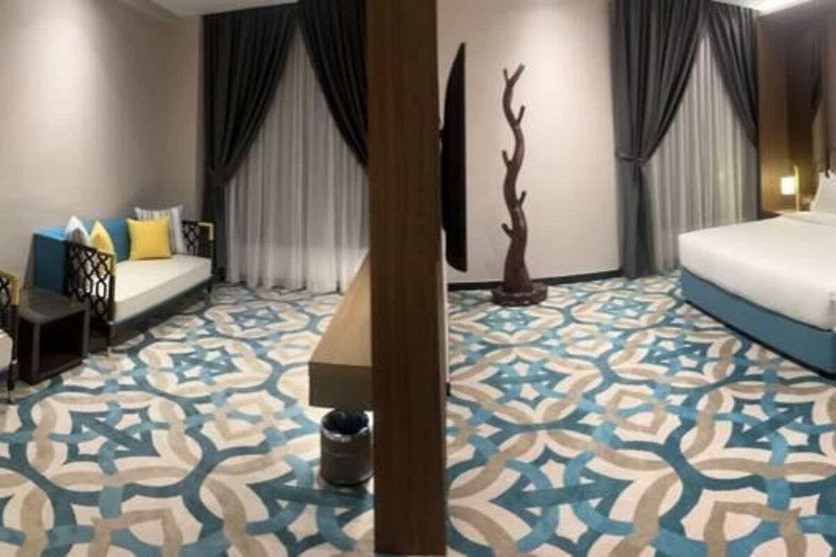 A hotel room with a large bed, a sofa, and a small table.