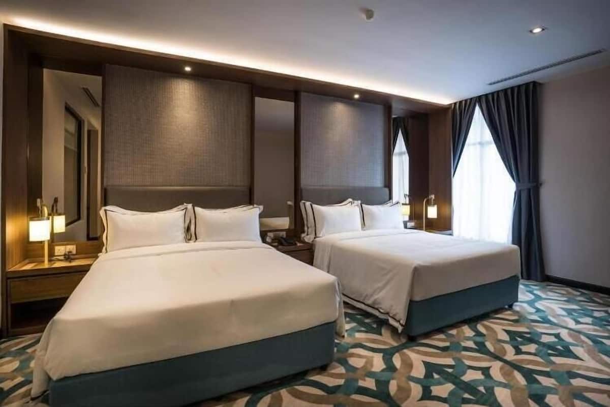 Una habitación de hotel con dos camas, un espejo grande y una alfombra estampada.