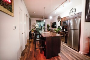 A modern kitchen with a central island, stainless steel appliances, and a dining area with bar stools.