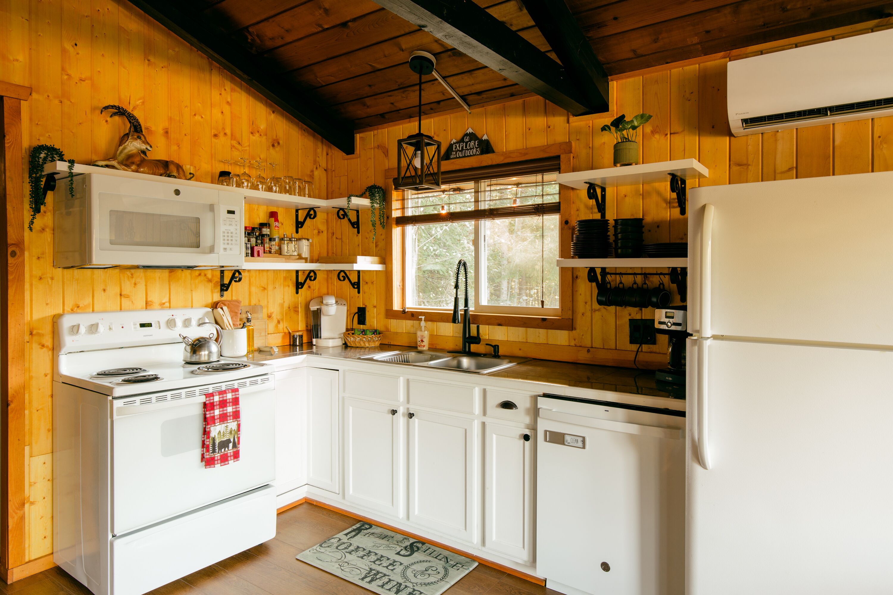 Una cocina con paredes de madera, una estufa blanca, un lavaplatos y un refrigerador.