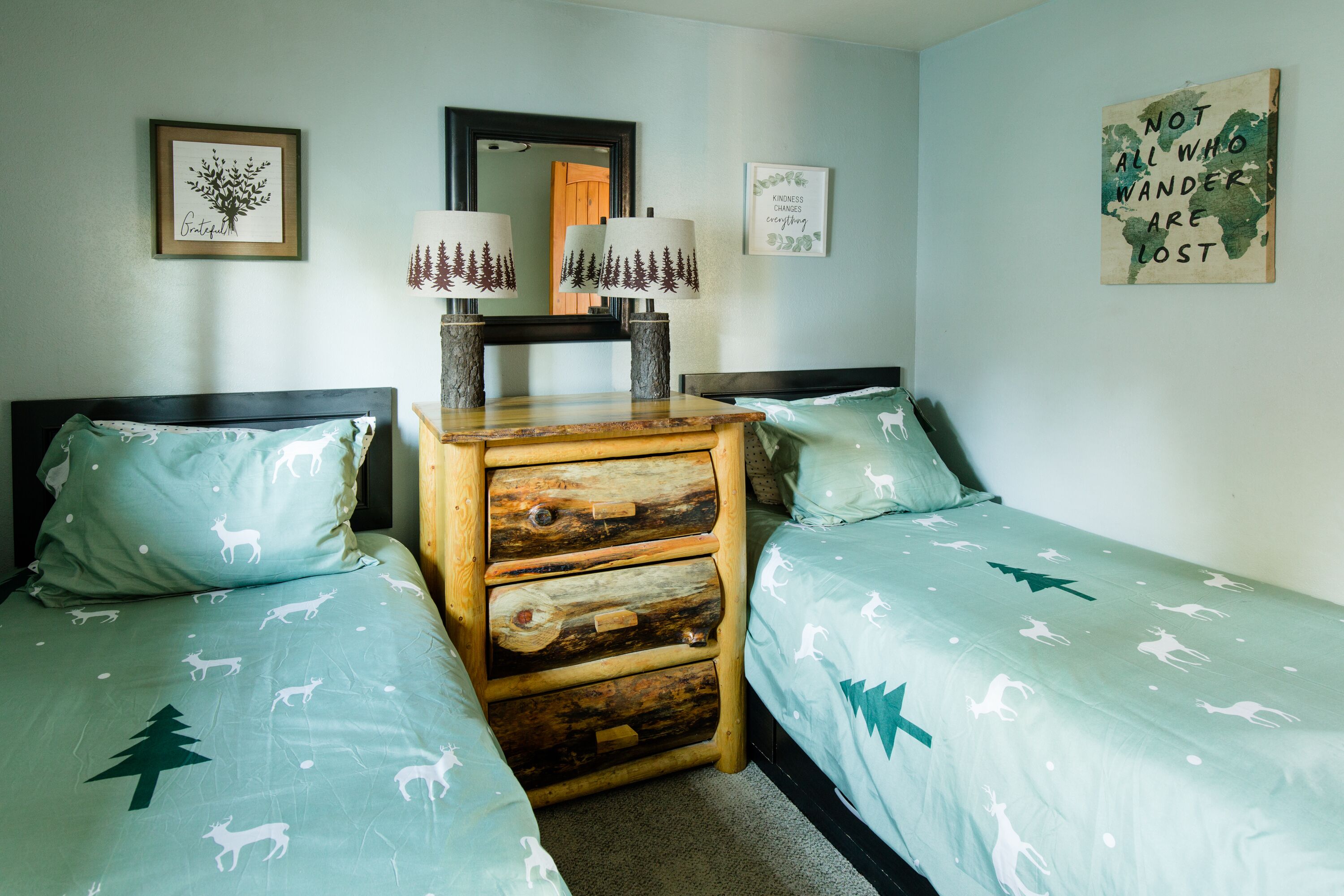 A bedroom with two beds, a dresser, and wall art.