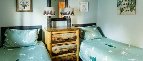 A bedroom with two beds, a dresser, and wall art.