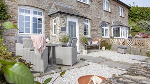 A stone building with a patio area featuring wicker furniture and a small table.