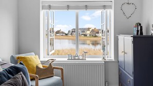 A room with a large window overlooking a body of water and houses.