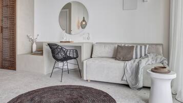 A modern living room with a sofa, a round mirror, a desk, a chair, and a small table.
