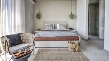 Un dormitorio con cama, mesitas de noche, una silla de mimbre y un tapete tejido.