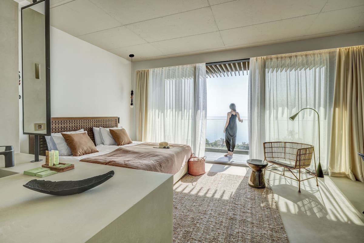 Ein modernes Hotelzimmer mit einem großen Bett, einem Schreibtisch und Blick ins Freie.