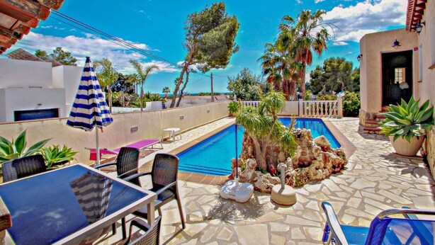 A pool area with lounge chairs, a table, and a striped umbrella.