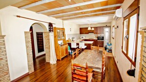 A spacious kitchen with wooden cabinets, a dining table with chairs, and a large window.
