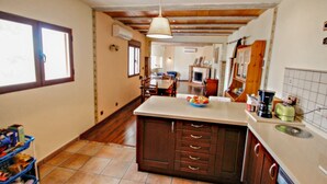 A kitchen with a central island, wooden cabinets, and a hanging light fixture.