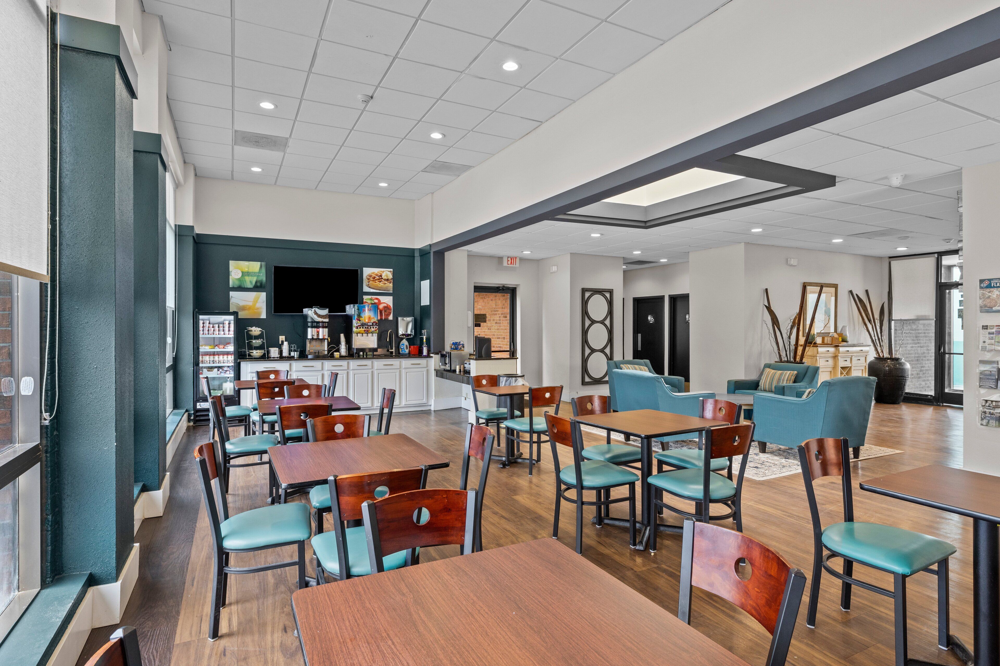 A spacious indoor area with multiple tables and chairs, a kitchen area, and a seating area with sofas and chairs.