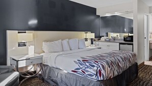 A modern hotel room with a large bed, bedside tables, a desk, and a microwave. - Garnet Inn & Suites, Morehead City near Atlantic Beach (Morehead City)