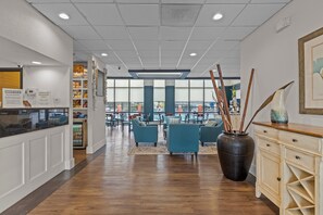 Eine geräumige Lobby mit Holzböden, Sitzbereichen und einer großen Vase mit Zweigen.