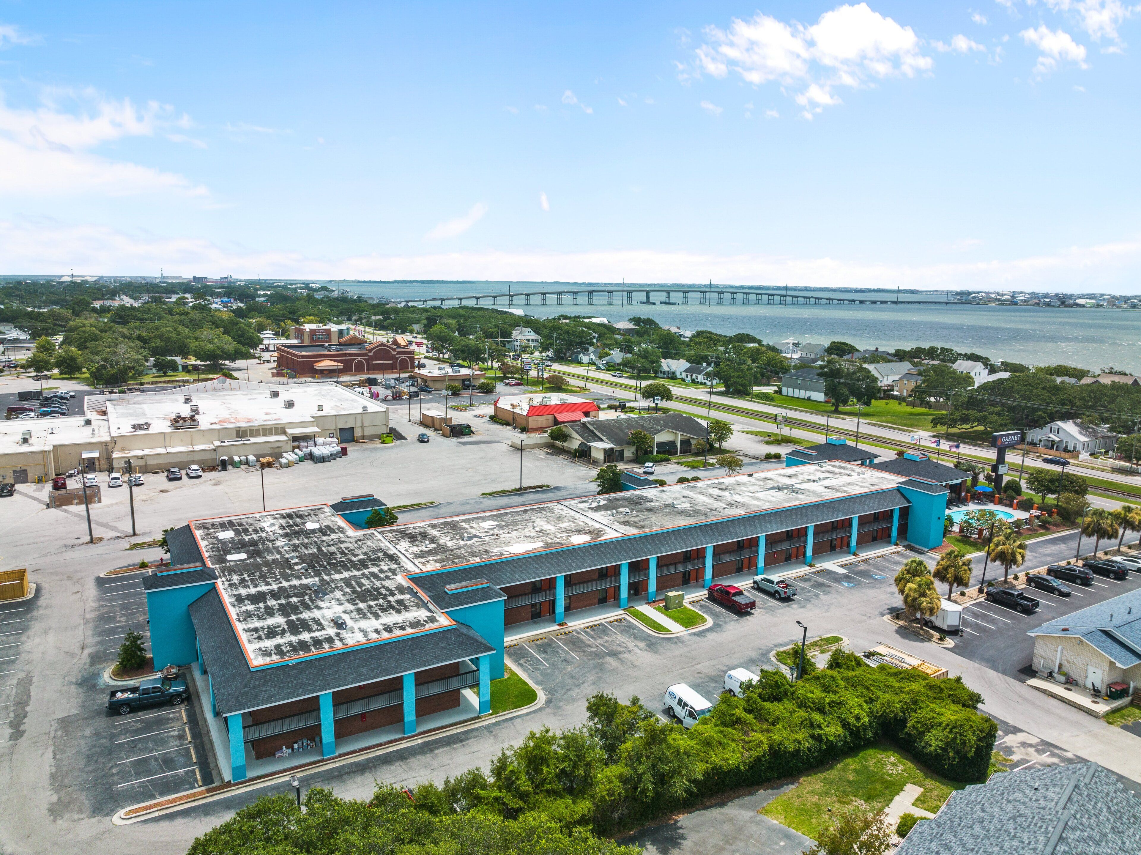 A large building with multiple parking spaces and a view of a bridge in the background.