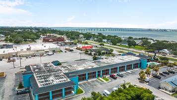 A large building with multiple parking spaces and a view of a bridge in the background.
