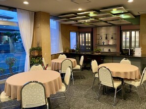 A hotel dining area with round tables, chairs, and a bar area with shelves. - Hitachi Hotel Crane (Hitachi)