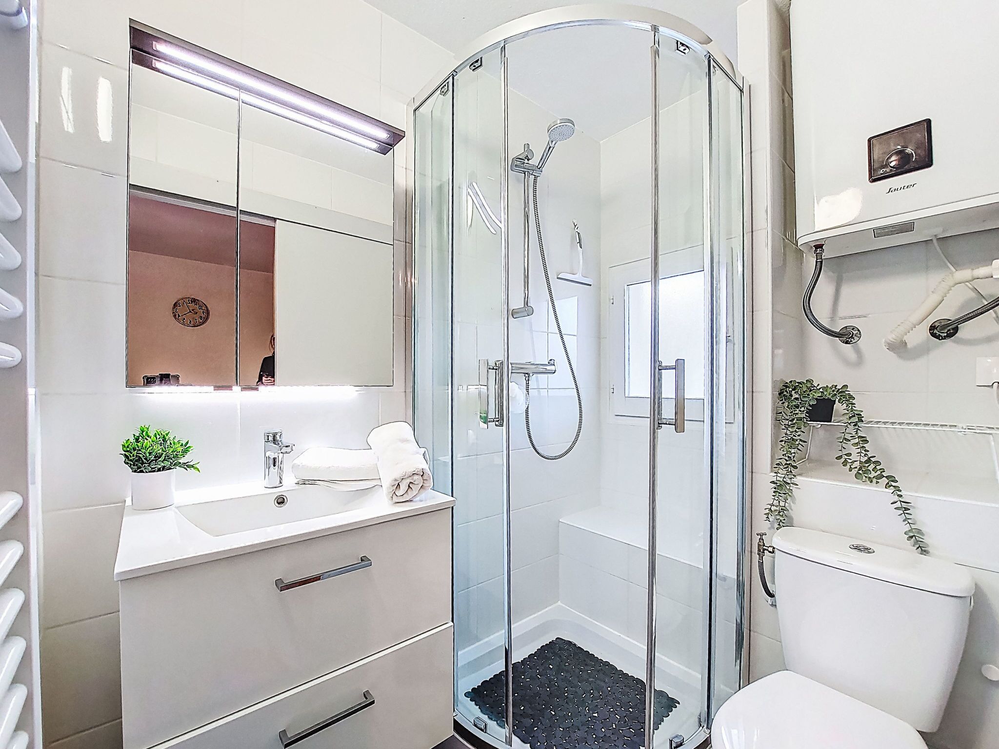 A modern bathroom with a glass-enclosed shower, a white sink, and a mirror above the vanity.