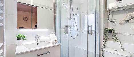 A modern bathroom with a glass-enclosed shower, a white sink, and a mirror above the vanity.