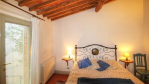Un dormitorio con una cama, dos lámparas de noche, una silla y una ventana con persianas.