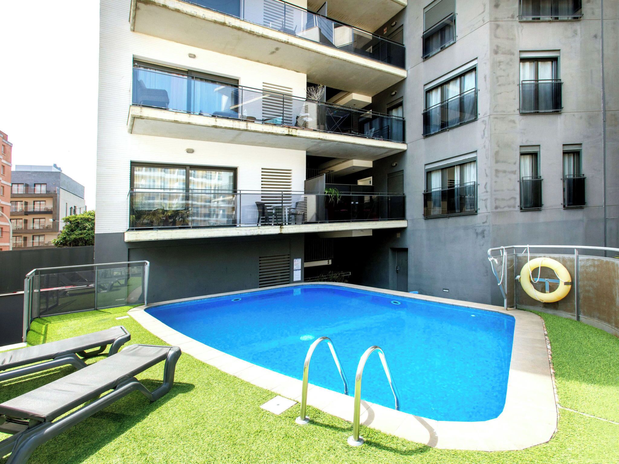 Un bâtiment moderne doté d’une piscine, d’un espace extérieur aménagé et de balcons.