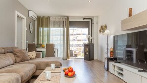 A modern living room with a sofa, a dining table with chairs, a TV, and a fireplace. - Jessmart by Interhome (Lloret de Mar)