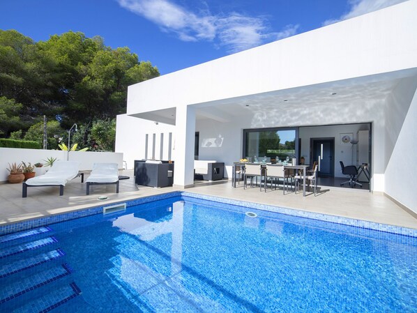 A modern outdoor pool area with a dining setup and lounge chairs.
