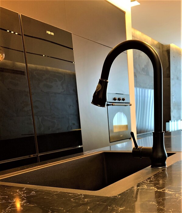 Una cocina moderna con un grifo negro, horno empotrado y una elegante salpicadera.