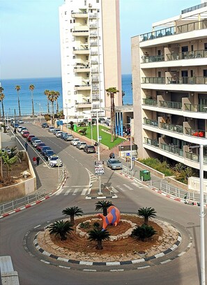 Stroll through the vibrant coastal streets, surrounded by multi-story buildings with balconies and palm trees.