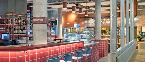 A modern bar area with a red tiled counter, blue bar stools, and a liquor display.