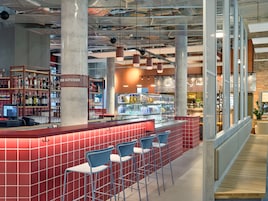 A modern bar area with a red tiled counter, blue bar stools, and a liquor display.