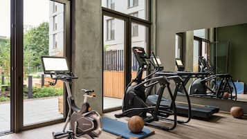 A modern gym with stationary bikes, treadmills, and a rowing machine.