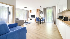 Un salon moderne comprenant un canapé, un coin repas avec des chaises, un téléviseur et une cuisine équipée d’une cuisinière.